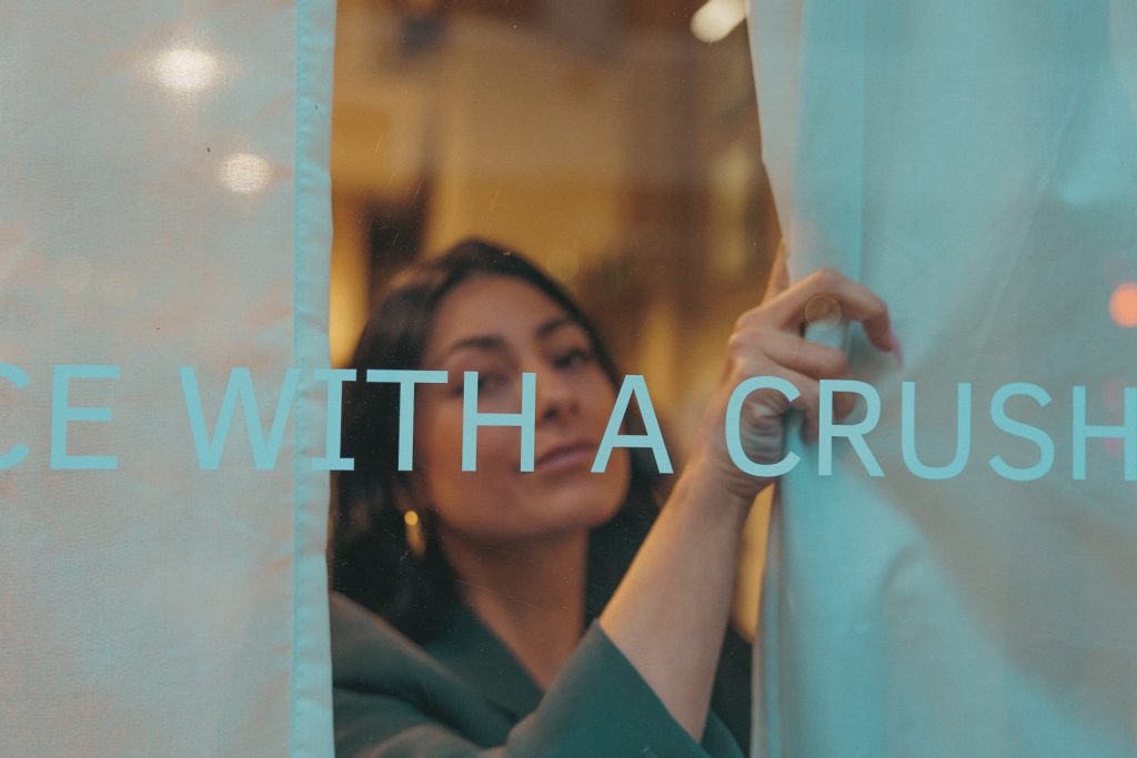 Erika Vasquez adjusts the curtains inside the River event venue behind the lettering: AN EVENT VENUE WITH A CRUSH ON CREATIVES