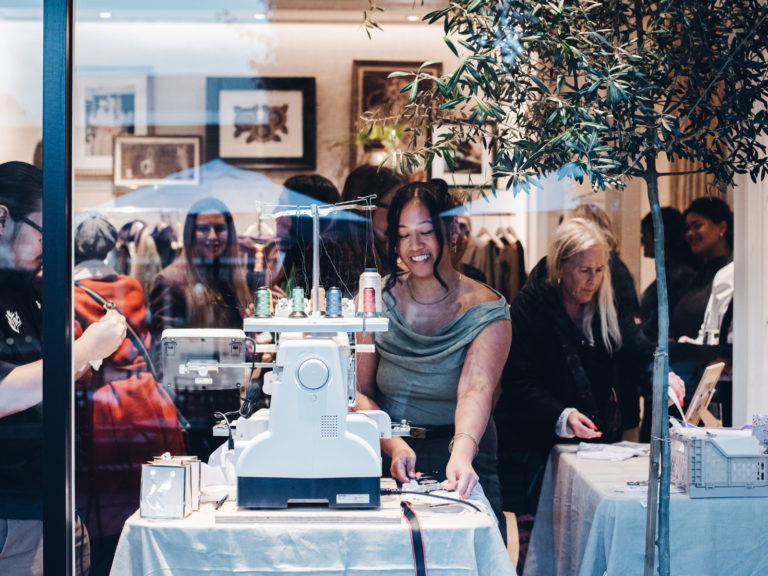 A crowd gathers around a live embroidery machine during a Tita Bun Co. event in Seattle.